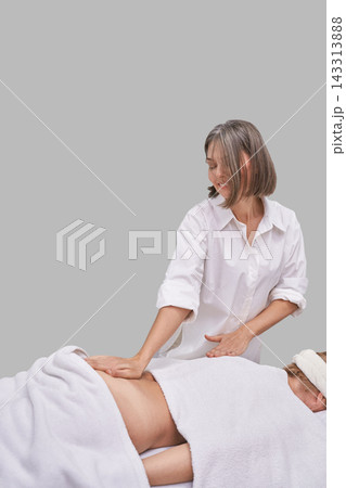 Female Massage Therapist Performing Abdominal Treatment On Reclining Client With White Towel Female Massage Therapist Performing Abdominal Treatment On Reclining Client With White Towel 143313888