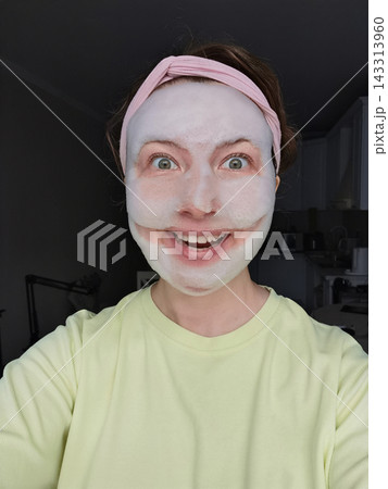 Woman Opens Mouth In Broad Smile While Wearing White Facial Mask And Pink Headband Woman Opens Mouth In Broad Smile While Wearing White Facial Mask And Pink Headband 143313960