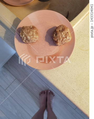 Two Browned Patties And Curved Liquid Streak Resemble Smiling Face On Pink Plate Beside Sink Two Browned Patties And Curved Liquid Streak Resemble Smiling Face On Pink Plate Beside Sink 143314041
