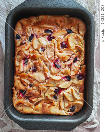 Rectangular Fruit Cake Rests In Dark Baking Pan, With Golden Apple Slices And Scattered Red Berries 143314208