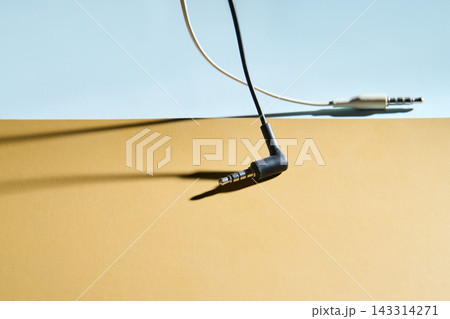 Black Angled Headphone Jack Lying On Two Tone Surface With White Cable And Metal Plug Casting Long 143314271