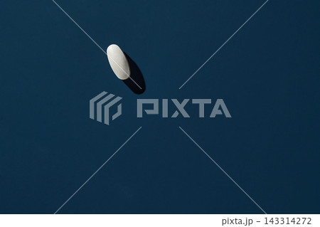 Single White Oval Tablet Resting On Dark Blue Surface With Crisp Shadow And Minimalist Negative 143314272