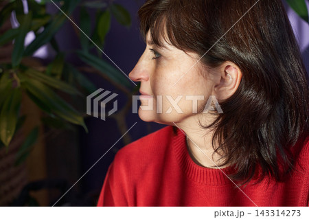 Woman Looking Sideways In Indoor Setting Wearing Red Sweater Near Potted Plant With Soft Natural Woman Looking Sideways In Indoor Setting Wearing Red Sweater Near Potted Plant With Soft Natural 143314273