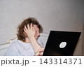 Woman Covering Forehead With One Hand While Facing Laptop In Bed, Showing Fatigue, Headache 143314371