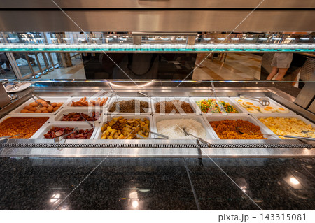 International breakfast buffet featuring eggs, sausages, bacon, rice, potatoes, vegetables, and baked beans in hotel restaurant. 143315081