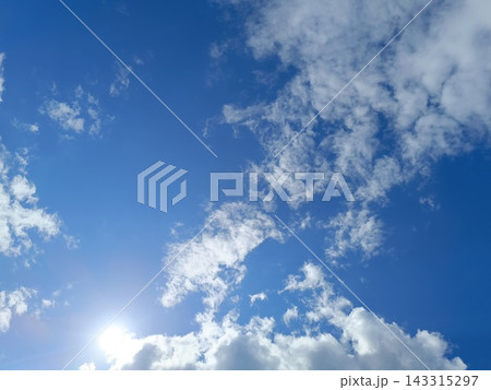 Bright sun shining in a blue sky with white clouds. Sunny summer day background Bright sun shining in a blue sky with white clouds. Sunny summer day background 143315297