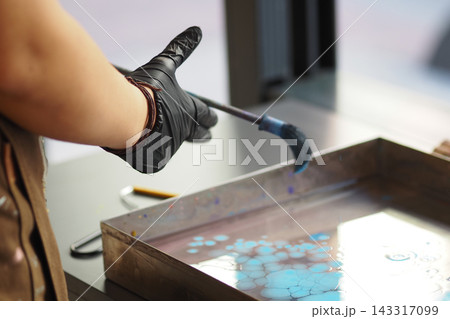 Man creates art using a brush and colored water in a studio setting Man creates art using a brush and colored water in a studio setting 143317099