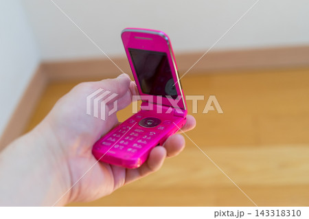 ピンク色のガラケーを持つ 143318310