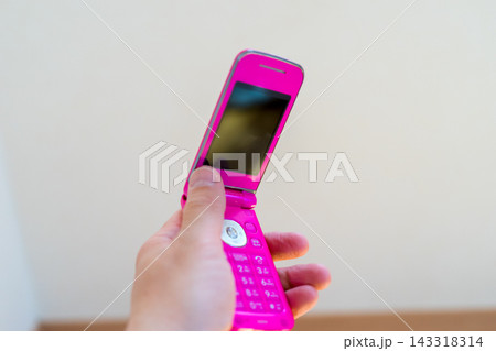 ピンク色のガラケーを持つ 143318314