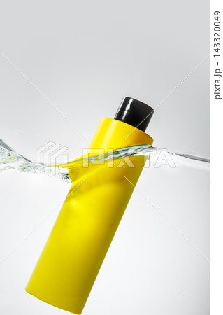 Floating Yellow Cosmetic Bottle in Water Splash 143320049