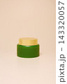 Green cream jar on beige background 143320057
