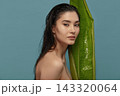 Tropical woman peeking out from behind exotic plant big leaf. 143320064
