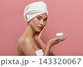 Girl wrapped in white hair turban holds cream jar. 143320067