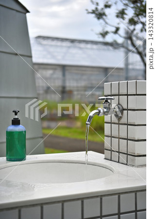 手洗い場の水が出ている蛇口と液体せっけん 143320814