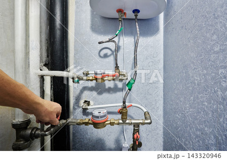 Plumbing manifold consists of operational water meters plus control valves and flexible lines under domestic storage water heater container. Plumbing manifold consists of operational water meters plus control valves and flexible lines under domestic storage water heater container. 143320946
