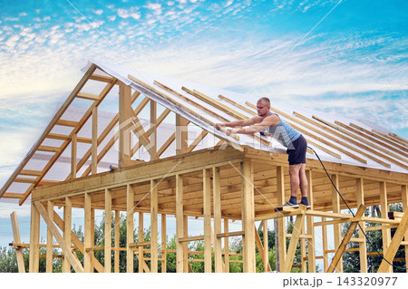 Fastening timber counter battens over roofing membrane for roof ventilation by construction worker. Fastening timber counter battens over roofing membrane for roof ventilation by construction worker. 143320977