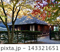 赤や黄色に色づく秋の紅葉に囲まれた茅葺き屋根の伝統的な木造家屋、日本の秋を感じる古民家風景 143321651
