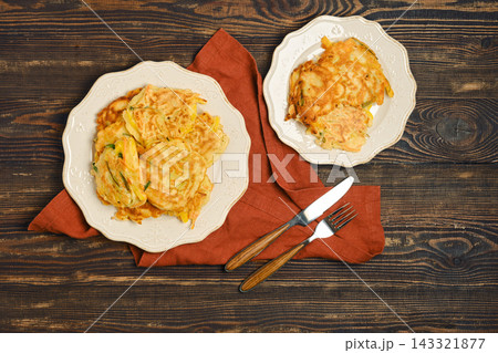 Home cooking vegetable fritters served on plates with cutlery on wooden table 143321877
