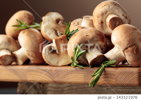 Mushrooms with rosemary on a wooden cutting board. Mushrooms with rosemary on a wooden cutting board. 143321976