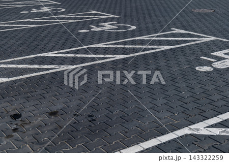 A clearly marked parking space for disabled individuals is visible on the ground in a parking lot during daylight hours A clearly marked parking space for disabled individuals is visible on the ground in a parking lot during daylight hours 143322259