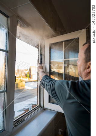 Cleaning the window. A man with steam device removes dirt from the plastic window frame. 143323702