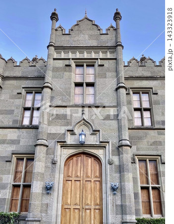 Gothic Revival stone palace facade features symmetrical windows and grand wooden entrance. 143323918