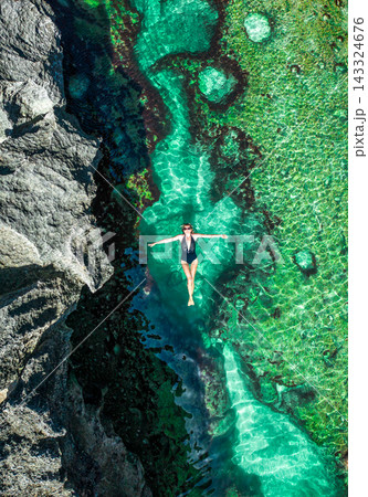 Aerial top view of a girl lying in the water on rocky the Angels Billabong in Nusa Penida island 143324676
