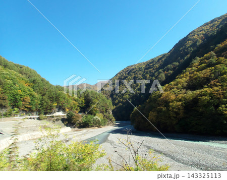 秋の紅葉に染まる山間の川 143325113