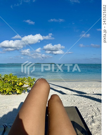 Traveler relaxes on beach lounger overlooking turquoise ocean under sunny sky. Traveler relaxes on beach lounger overlooking turquoise ocean under sunny sky. 143325882