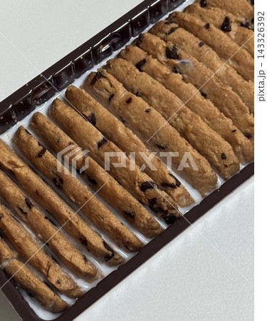Cookies being enjoyed with a glass of milk, featuring a soft bite and rich sweetness balanced by creamy freshness. A cozy, nostalgic moment that feels warm, simple, and comforting. 143326392