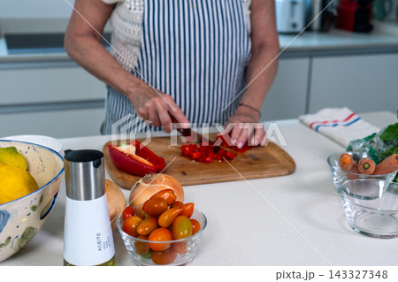 Woman dicing red peppers with precision at a bright kitchen counter Woman dicing red peppers with precision at a bright kitchen counter 143327348