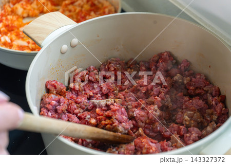 Browning seasoned ground meat in a white pot during empanada filling preparation Browning seasoned ground meat in a white pot during empanada filling preparation 143327372