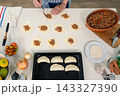 Distributing seasoned meat filling across fresh empanada rounds with practiced precision 143327390