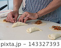 Folding empanada dough around savory meat filling with skilled hands 143327393