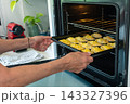 Placing golden empanadas into a preheated oven with determined purpose 143327396