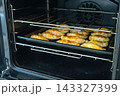 Golden empanadas baking on a dark tray in a preheated oven 143327399
