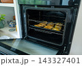 Golden empanadas baking on a dark tray inside an open modern oven 143327401