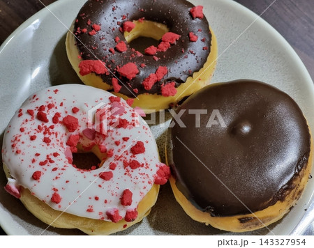 Delicious doughnuts with a golden, fluffy texture, topped with colorful glazes and sprinkles. Perfect for dessert or breakfast photography, showcasing the sweet indulgence of these classic treats. Delicious doughnuts with a golden, fluffy texture, topped with colorful glazes and sprinkles. Perfect for dessert or breakfast photography, showcasing the sweet indulgence of these classic treats. 143327954