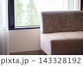 窓際にカウチソファのあるリビング。庭が見える明るい部屋。 143328192