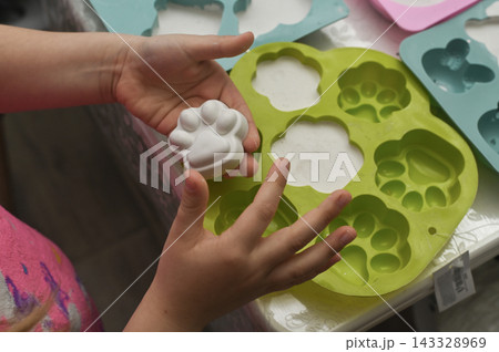 Kid displays plaster figure after removing it from soft tray. 143328969
