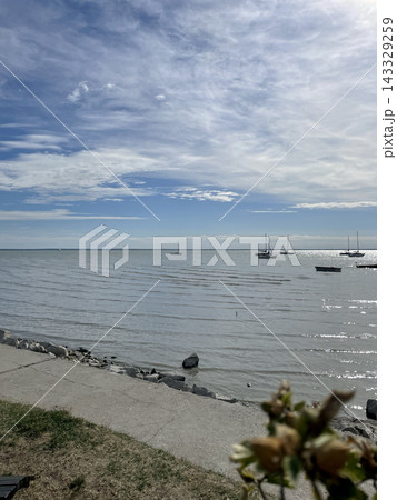 Wide cloudy sky over calm Lake Balaton with sailing yachts and stone embankment, Hungary Wide cloudy sky over calm Lake Balaton with sailing yachts and stone embankment, Hungary 143329259