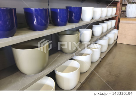 Colorful ceramic planters displayed on shelves in a garden store, featuring blue, white, and neutral pots for home decor, gardening, and seasonal planting ideas. Colorful ceramic planters displayed on shelves in a garden store, featuring blue, white, and neutral pots for home decor, gardening, and seasonal planting ideas. 143330194