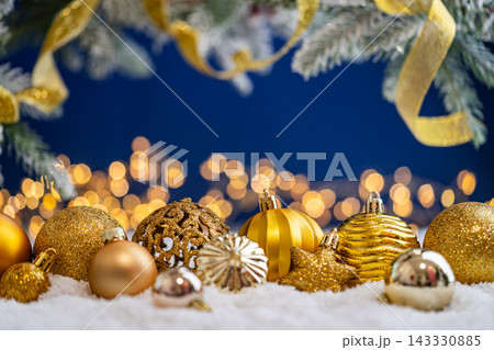 Gold Christmas Ornaments with Ribbon on Snow, Blue Backdrop Gold Christmas Ornaments with Ribbon on Snow, Blue Backdrop 143330885