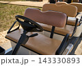 Front Golf Cart Seat And Steering Wheel Parked On Sunny Path Beside Grassy Fairway At Resort Course 143330893