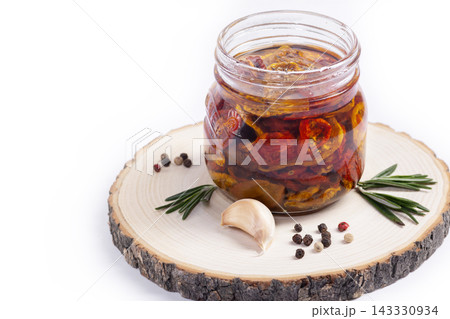 Dried tomatoes with spices in olive oil in a jar, isolated. Dried tomatoes with spices in olive oil in a jar, isolated. 143330934