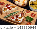 Snacks and sandwiches with dried tomatoes on wooden board. 143330944