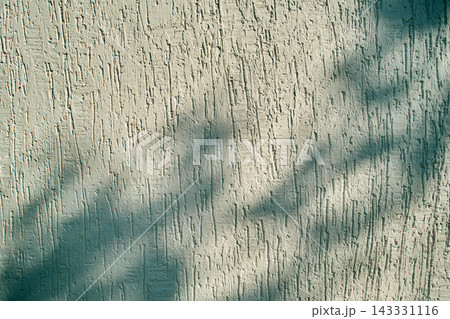 Abstract light and shadow pattern on a beige textured stucco wall 143331116