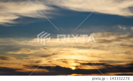 bright sun setting behind dark clouds in a golden sunset sky bright sun setting behind dark clouds in a golden sunset sky 143332278