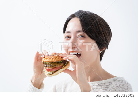 美味しいハンバーガーを食べる笑顔の女性 美味しいハンバーガーを食べる笑顔の女性 143335605
