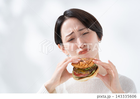 ハンバーガーを食べるか悩むダイエット中の女性 ハンバーガーを食べるか悩むダイエット中の女性 143335606